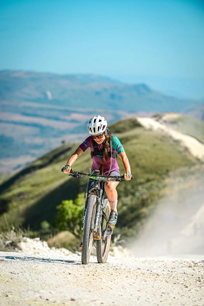 Ciclista sobe uma estrada de terra entre montanhas